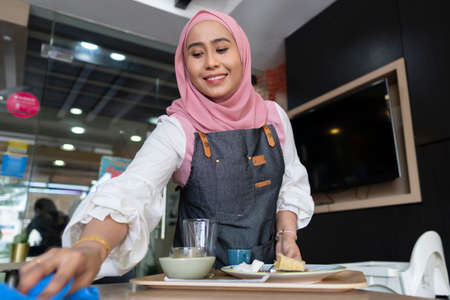 Business Concept : Young restaurant waiter preparing table for customerの写真素材