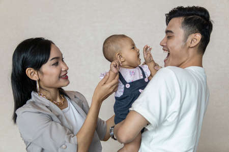 Family moment: Young malay couple with toddler smiling to each other focusing on the toddler