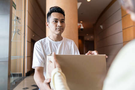 Young Malay guy holding a box representing delivery guy
