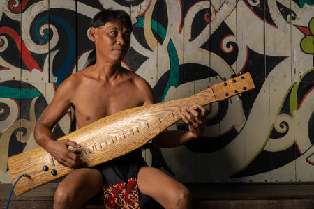 Kuching, Sarawak - 13 May 2022: Traditional Dancer at Sarawak Village, demonstrate his traditonal guitar called sapeのeditorial素材