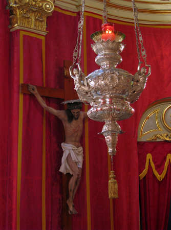 A silver lamp in the foreground with a Crucifix in the background in Floriana, Malta のeditorial素材