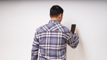 Back view of a man looking to the mobile phone that he holdの写真素材