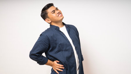 Young Asian man wearing shirt suffer low back pain on white background