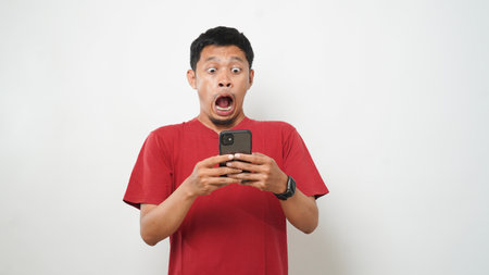 Wow face of Asian man shocked what he see in the smartphone on isolated grey background.の写真素材