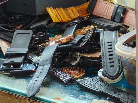 A cluttered assortment of watch straps and parts, including leather, rubber, and metal bands, are...