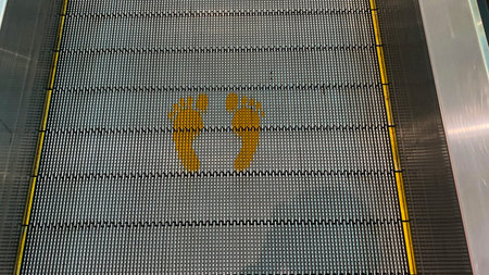A top-down view of an escalator step shows two yellow footprint markings, indicating where to stand.