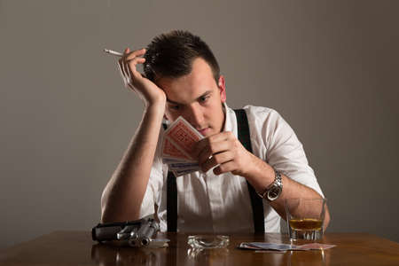 portrait of young man smoking and play poker with gun