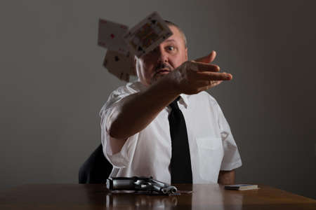 Businessman throwing playing cards at the tableの写真素材