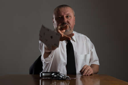 Businessman throwing playing cards at the table
