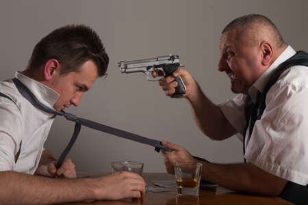 View of two businessman playing poker and having fight with gunの写真素材