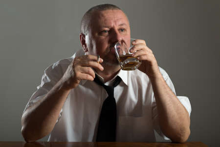 Businessman drinking alcohol and smoking cigaretteの写真素材