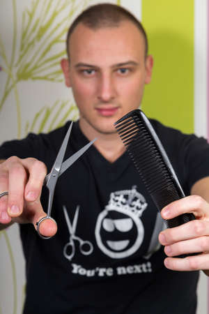 Hair stylist holding in hand scissors and hairdresser equipment.