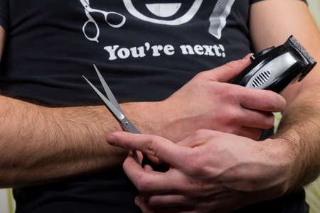 Hair stylist holding in hand scissors and hairdresser equipment wearing T-shirt