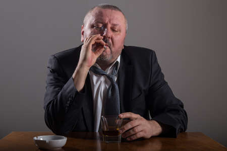Business man with a glass of whiskey and cigaretteの写真素材