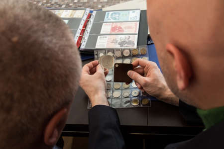 Two numismatists examines  collection of coin