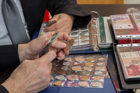 Two numismatists examines  collection of coinの写真素材