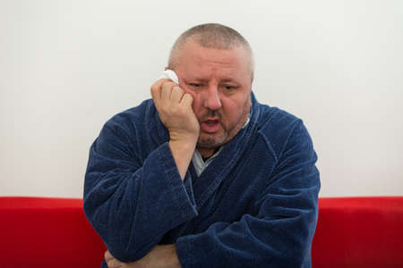 Close-up of a man with tissue in his nose.