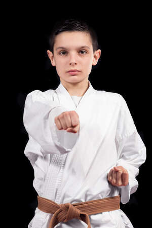 Karate boy in white kimono fighting isolated on black  background.の写真素材