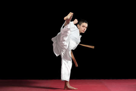 Karate boy in white kimono fighting isolated on black  background.の写真素材