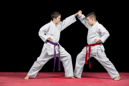 Two boys in white kimono fighting isolated on black background.の写真素材