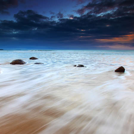 Moeraki Boulders on a dramatic sunrise with waves flowing over the bouldersの写真素材
