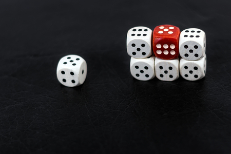 Worn white dices and one red on a black glossy backgroundの写真素材
