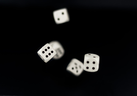 white dice roll in flight four and six in focus other motion blured