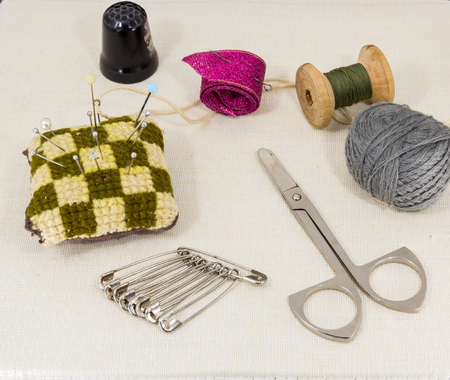 Textile fabric for sewing,accessories for needlework on new textile background. Spool of thread, scissors, thimble, tapemeasure , sewing supplies. Set for needlework top viewの写真素材