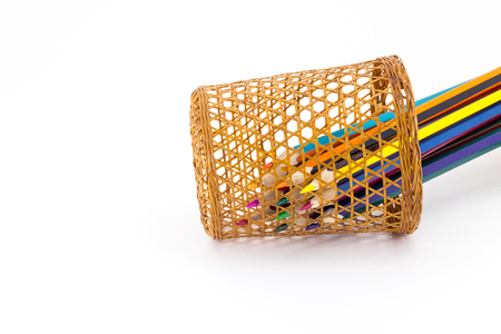 Sharp tips of colored pencils sharpen from sections of a wicker tube, on a white backgroundの写真素材