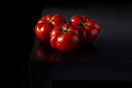 Juicy tomatoes on a wooden dark backgroundの写真素材