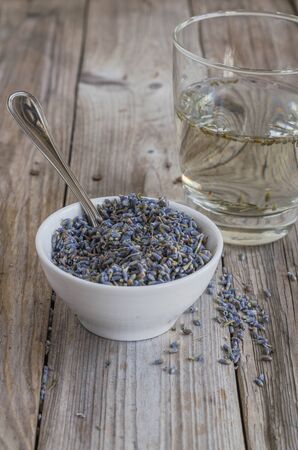 a white cup of dried lavender with stainless tea spoon on wood tableの写真素材