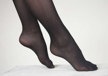 Close Up of woman s feet wearing dark sheer pantyhose against a white studio backgroundの写真素材
