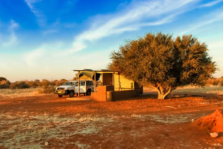 Pickup 4x4 car with a tent on the roof on road trip has a stop at a camping rest area in desolate nature landscape in the desert of Kalahari in Namibia, Africaのeditorial素材