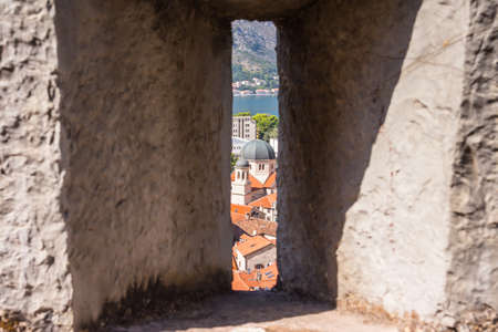 View of the Church of St. Nicholas through the loophole of the protective wall of the fortress in the town of Kotor. Montenegroの写真素材