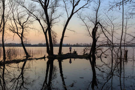 The silhouette of a man against the backdrop of the lake near the city of Kyiv at sunset. Ukraineの写真素材