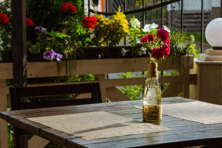 Red flowers in a bottle on the table in a restaurant. Table setting. Still lifeの写真素材