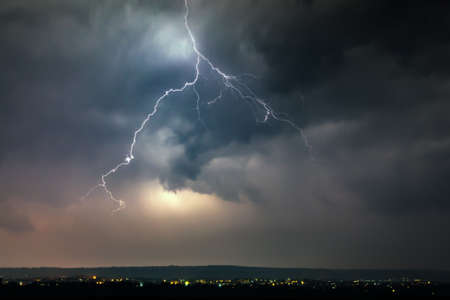 Lightnings over city during thunderstorm in the nightの写真素材