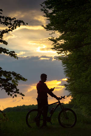 Silhouette of biker taking a picture at sunsetの写真素材
