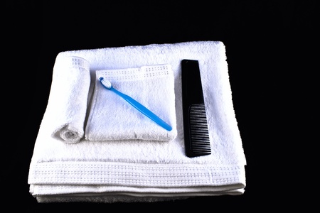 Pristine white towel and washcloths folded neatly, Blue toothbrush and black hair comb rest on topの写真素材