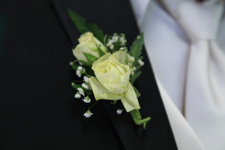 Off white flowers of this grooms boutonniere are pinned to his black lapel.