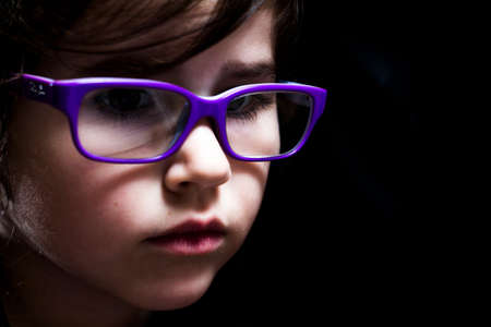 A portrait of a young girl with purple glasses and dramatic lighting.の写真素材