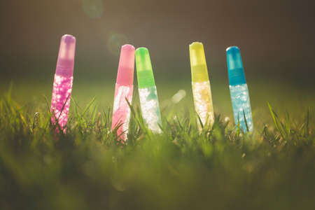 Glitter pens stand tall in a field of green grass.