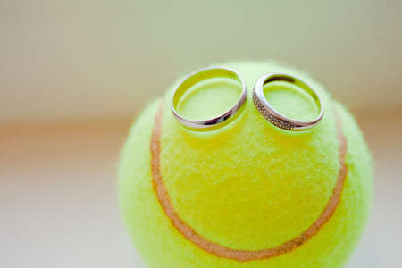 Wedding smile: two white gold ring with diamonds are on green tennis ball