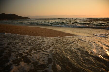 Dramatic scene at sunset of the waves breaking on the shorelineの写真素材