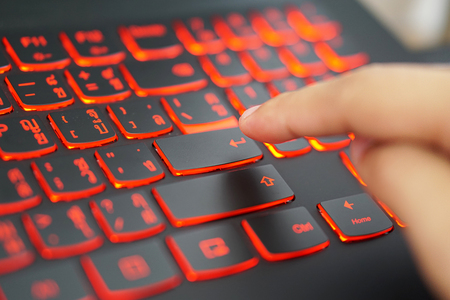 Finger going to presses the key "Enter" on a Thai-English language and red light keyboard for hacker,gamer,office concept,soft focusの写真素材