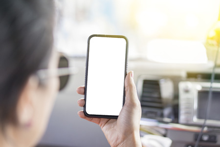 The middle-aged woman who wear sunglasses is touching mobile phone by forefinger while sitting on front seat in  carの写真素材