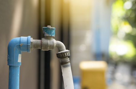 Blue brass water tap with rubber tube attach in the end with sun flaresの写真素材