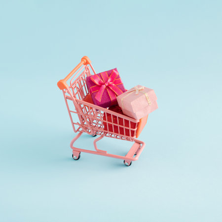 Gifts in the pink shopping cart on blue background. Creative minimal concept.の写真素材
