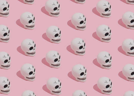 Halloween pattern made of skulls on pink background. Minimal Halloween concept.