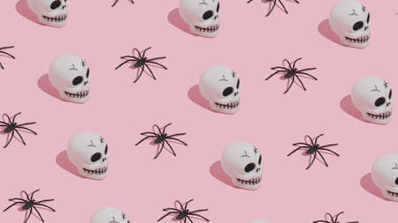Halloween pattern made of skulls and spiders on pink background. Minimal Halloween concept.の写真素材
